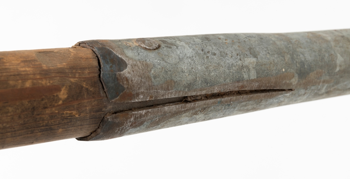 Ladestav, brukt i forbindelse med grøftesprening i skog og utmark, der man forsøkte å drenere vekk vann som virket veksthemmende på produksjonsskogen. Dette redskapet er 109,5 centimeter langt og består av en rett trestav med ovalt tverrsnitt, samt et 36 centimeter høyt sinkgalvanisert endebeslag, ei slags hylse, som omslutter den ene enden av staven. Ettersom denne delen av staven er litt kon, ser det ut til at beslaget egentlig er lagd av to komponenter med litt ulike diametere, Den øverste delen av beslaget har dessuten to sidespalter, som nok er en tilpasning til stavens noe økende tjukkelse fra ytterenden og oppover. Beslaget er forankret i trestaven ved hjelp av to gjennomgående nagler. Rundt den øvre enden av treskaftet er det viklet litt grå tape.