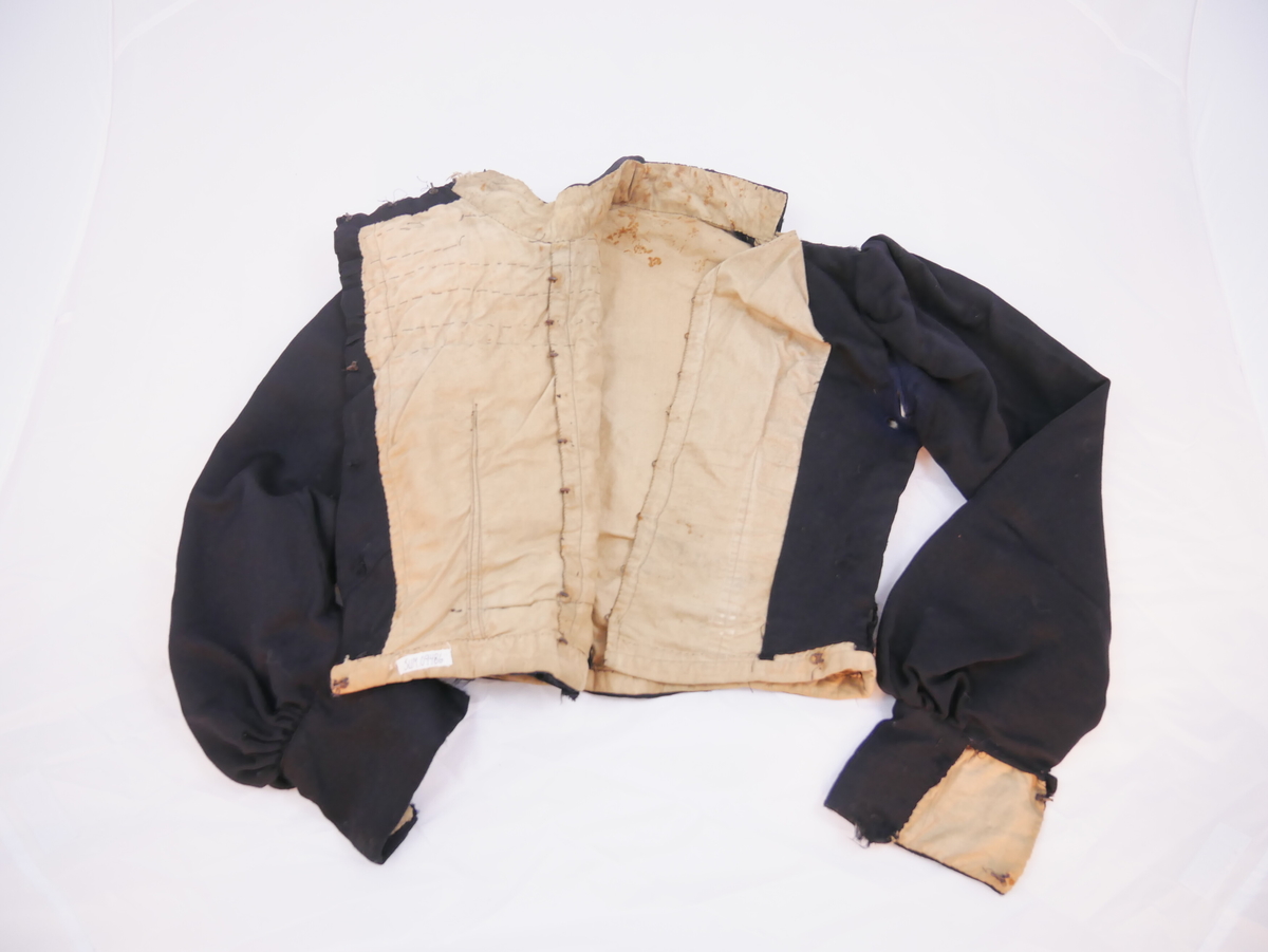 Kort overdel som høyrer saman med skjørt til kjole ("bykjole").
Har høg halslinning, ermene er rynka ved skuldrane og har breie ermkragar. Lukkinga er på venstre sida, slik at framstykket blir heilt. Dette er rynka i fleire felt med dekorativ verknad. Foret har lukking mist framme med ti sett hekter og hemper, det eine manglar.