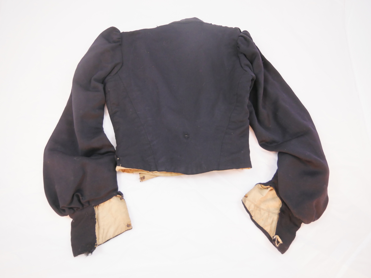 Kort overdel som høyrer saman med skjørt til kjole ("bykjole").
Har høg halslinning, ermene er rynka ved skuldrane og har breie ermkragar. Lukkinga er på venstre sida, slik at framstykket blir heilt. Dette er rynka i fleire felt med dekorativ verknad. Foret har lukking mist framme med ti sett hekter og hemper, det eine manglar.