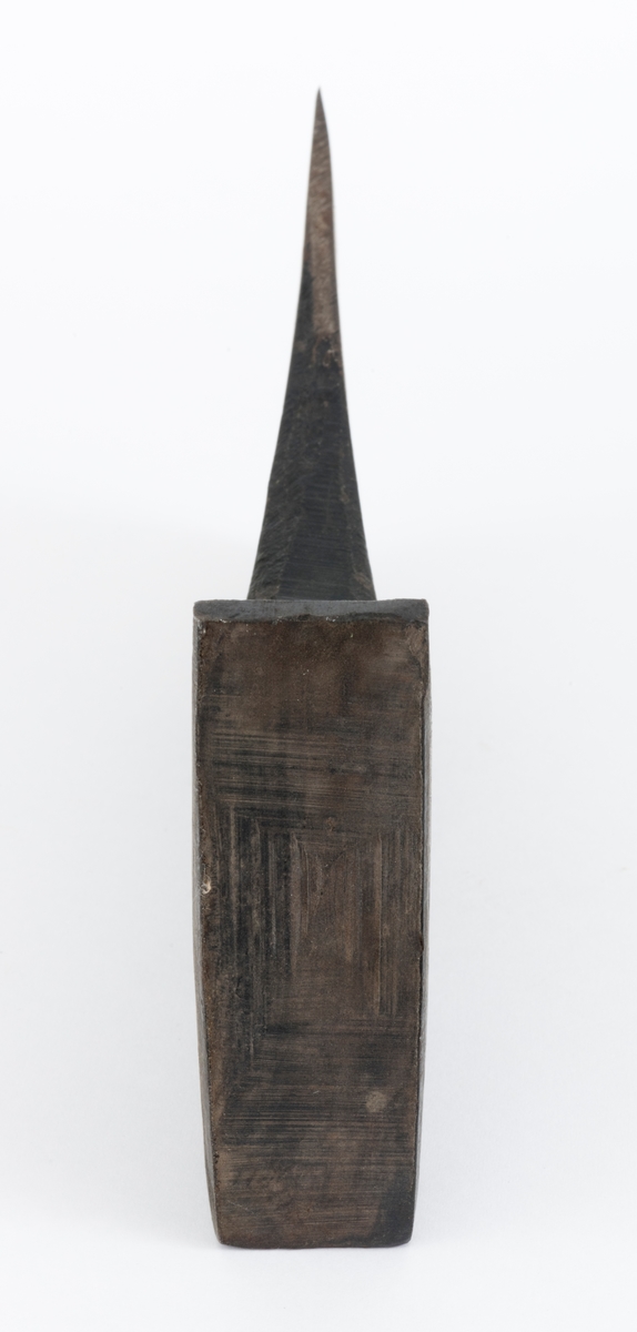 Uskjeftet øks fra produsenten O. Mustad & Søn på Gjøvik i Oppland. Øksehodet er 21,1 centimeter høyt, målt vinkelrett fra midten av den noenlunde plane nakkeflata ned mot den fremre delen av egglinja. Den nederste delen av øksebladet er 9,0 centimeter bred. Her er målet tatt i rett linje mellom den konvekse eggens ytterkanter. Den fremre tverrenden på øksehodet er noenlunde rettlinjet. På «baksida» skrår bladet noe innover mot et punkt like under «øyet» (skafthullet), der bredden er 5,7 centimeter. På denne sida øker bredden på «kjakene» mot den bakre enden av nakkepartiet. Hammerflata på denne delen av øksa er 9,6 centimeter langt og om lag 3,1 centimeter bredt bakerst, 2,8 i den fremre enden. På den høyre sida av øksenakken (sett i øksebrukerens perspektiv) finnes et svakt preget ovalt stempel med teksten «MUSTAD ØKS». Den øvre delen av øksehodet er svartlakkert, mens ei cirka 5,5 centimeter bred sone nederst på bladet er stålblank.