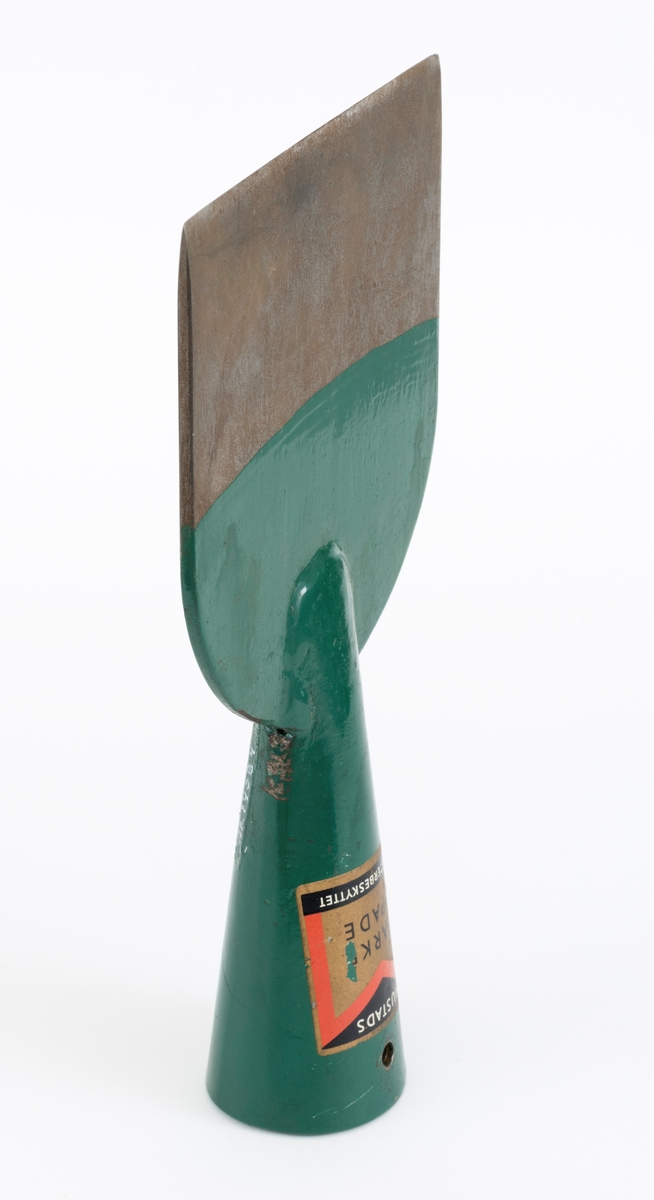 Barkespade fra O. Mustads fabrikker. Barkespaden består av ei plan stålplate med ei påsveiset, kon stålhylse i forlengelsen av bladets midtakse, i overenden.  Bladet er 12 centimeter bredt ved eggen, og egglinja er ubetydelig konvekst buet.  Den øvre enden av bladet var derimot tydelig buet, nærmest halvsirkelformet.  Her er bladet drøyt 4 millimeter tjukt.  Falen er lagd av 3 millimeter tjukt stål.  Den er tilpasset en kjegleformet skaftende og har et gjennombrutt hull med cirka 5 millimeters diameter, antakelig for en skrue eller spiker som skulle forebygge at stålet løsnet fra treskaftet.  Den øvre delen av bladet og falen er innsatt med mørkegrønn lakk.  På falens ytterside er det påsatt en rektangulær etikett med en rød «M» for Mustad på gullfarget og svart botn.  På den samme etiketten finner vi teksten «MUSTADS BARKESPADE MØNSTERBESKYTTET».  Denne barkespaden har ingen nevneverdige slitasjespor som kan tyde på at den har vært brukt i skogen, og den har sannsynligvis aldri vært skjeftet.