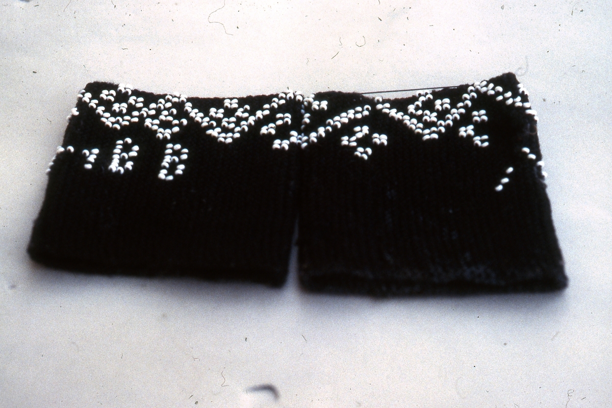 I början av 1800-talet kom pärlor att användas i stickning. Det var modernt i högreståndshem, där man stickade små väskor.

Muddar i ullgarn med instickade pärlor blev modernt hos allmogen i mitten av 1800-talet. Då blev tunna stålstickor och färgade glaspärlor billigare och mer lättillgängliga. Mönster hämtades från märkduksbroderiernas korsstygnsmönster som var lätta att överföra till pärlstickning. Muddarna var som smycken men värmde också handlederna.

I Jämtland och Härjedalen finns flera fina pärlstickade muddar bevarade.

Fotot (bild 4) föreställer Anna Helena Björkebaum.

/Ingela Fredell, 2024-03-26