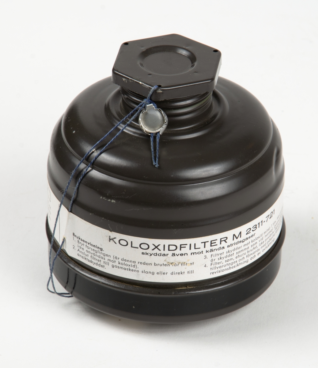 1. Gasmask med tygväska. Innehåller även instruktionsbok..
2. Gasmask av gummi med filter Typ 21.
3. Filter till gasmask, koloxidfilter M2311-721.