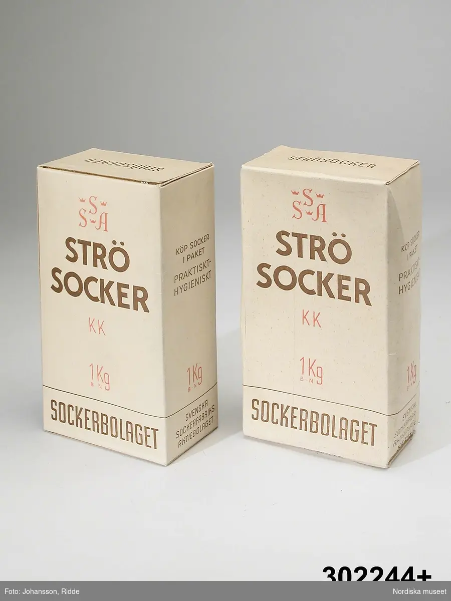 Huvudliggaren 1976:
”Förpackning, 2 st pappkartong, fyrkantig; vit med text i brunt och blått ’SSA Strösocker KK 1 kg Sockerbolaget’. Mått 17,5 x 10 x 6,2 cm. Gåva den 8/6 1976 från Laura Stridsbergs dödsbo, Lennart Björkner, Stockholm.”