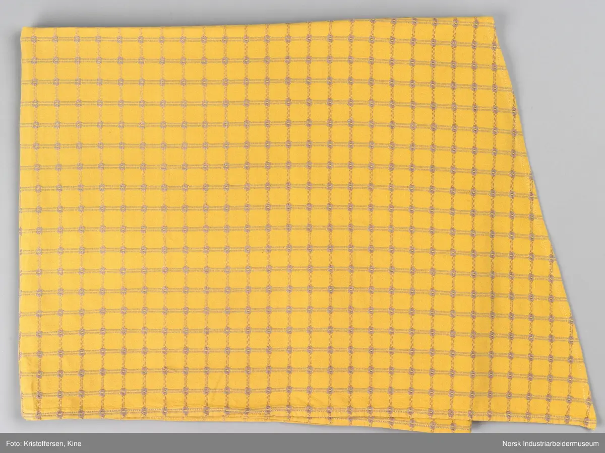 Gult stoffstykke satt sammen av tre stykker. Det er skjøtet 37 cm. fra høyre kant oppe. Pen skjøt, følger mønsteret. Jarekantene er ikke klippet av, men ligger på baksiden som sømningsmonn. På den andre siden, venstre side, er det satt på et lite stoffstykke ekstra. Det er gjort på samme måte, altså med en pen skjøt der mønsteret stemmer. Det er smale falder rundt hele stykket, men i overkant er den litt bredere. Det er et hull i stoffet. Stoffet er generelt ikke veldig slitt, og det virker ikke som dette hullet er forårsaket av alminnelig slitasje. Det må snarere være resultat av en spesiell påvirkning på akkurat det stedet. Pålimt lapp: F 09.