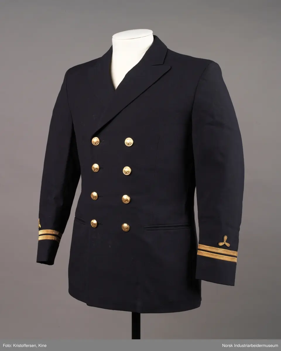Uniformsjakke til maskinist med åtte gullknapper med ankerlogo. To striper og propellogo i gull på hvert erme.