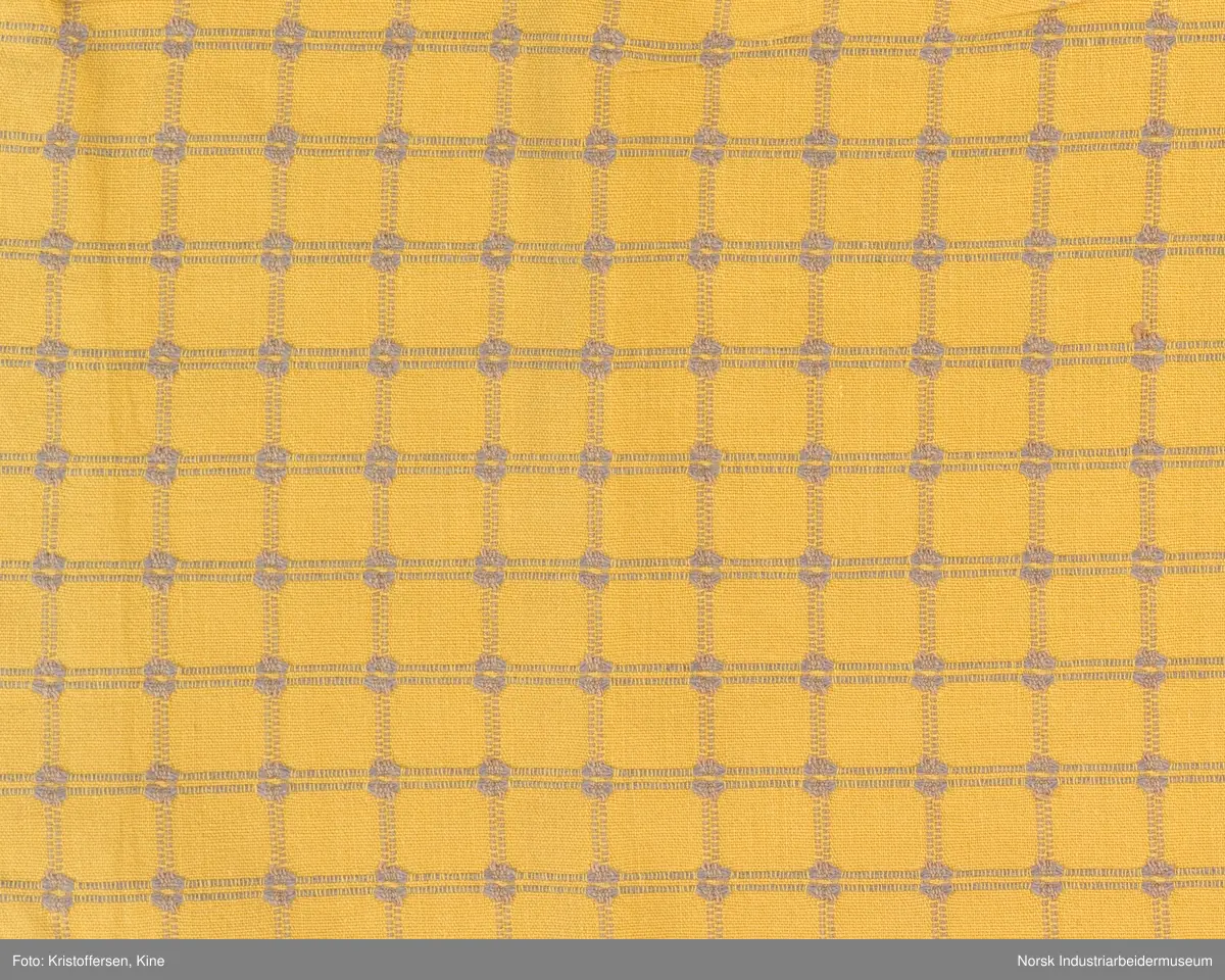 Tekstilpose. Det er søm i den ene siden av posen. Sømmen er en indresøm, det vil si ingen synlige falder og ikke noe stoff som kan trevles opp eller løse tråder på innsiden av posen. Bunnen er sydd av et rundt stoffstykke. Den er festet til posen med en vanlig søm, og kantene er kastet over for hånd. Det er løpegang oppe med bendelbånd gjennom. Dette kan ha vært et trekk til en pute, for eksempel en nakkepute, en pute som ligger i kortendene på en sofa eller seng som res opp om dagen. Det sitter en merkelapp på innsiden av sømmen i øverste kant. Det er en hvit lapp med rød skrift (maskinbroderi). Elektriker. Ovenfor dette merket er det sydd noen få, ujevne sting med beige brodergarn. Dette kunne ha vært en reparasjon, men det er ingen synlige skader i stoffet som skulle tilsi noe slikt. Det kan også være en vaskerimerking, eventuelt rester av en vaskerimerking. Det er også feste en liten, oransje tråd i kanten oppe. Det finnes noe liknende på andre av tekstilene – noe som kan tyde på at det er en merking som sier noe om avdelingen tekstilet hører til – eller det kan være en vaskerimerking. Det er søm i den ene siden av posen.