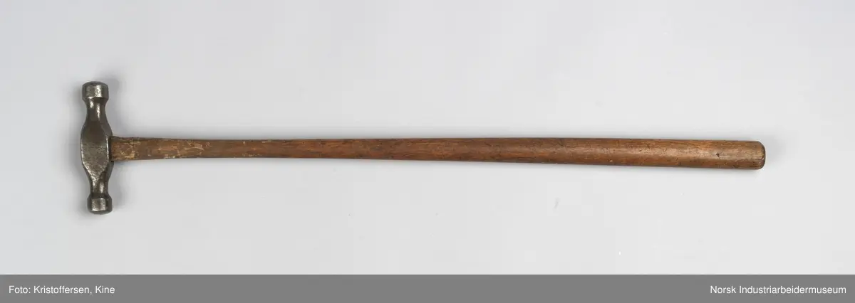 Vognvisitørhammer. Skaftet er gjennomgående. Hodet er blankslitt, metallisk av farge. Hodet har nok vært litt slarkete, for det er satt i en skrue i treverket i toppen for å utvide det slik at hammerhodet sitter godt på. Ingen stempler eller merker.