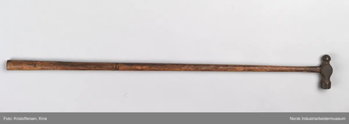 Vognvisitørhammer. Skaftet er 79 cm. langt. Skaftet er gjennomgående. Hodet er veldig svart og sitter litt slarkete. Merking: Lok. 9 er svidd inn. På hammerhodet står det: ½ lbs. Germany. Det er også et stempel i form av en stigbøyle