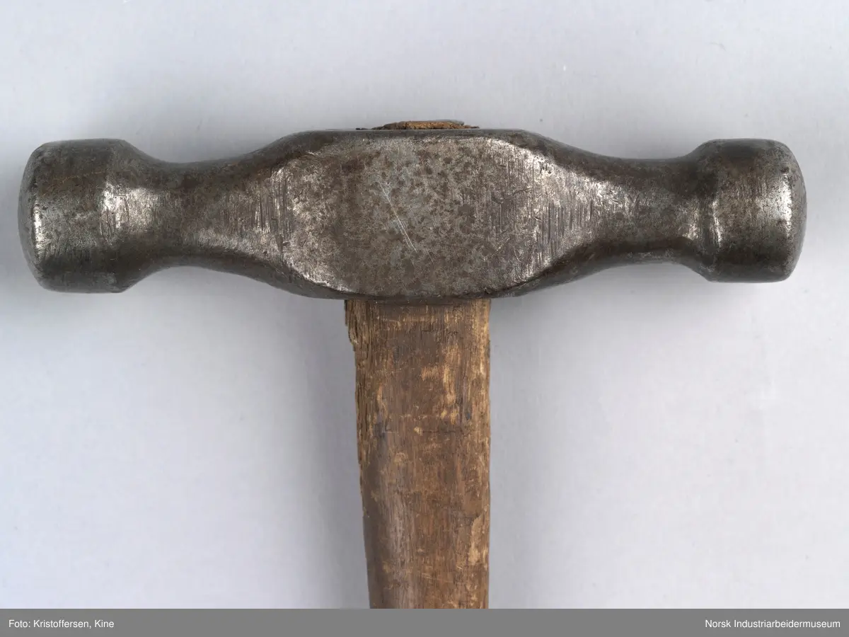 Vognvisitørhammer. Skaftet er gjennomgående. Hodet er blankslitt, metallisk av farge. Hodet har nok vært litt slarkete, for det er satt i en skrue i treverket i toppen for å utvide det slik at hammerhodet sitter godt på. Ingen stempler eller merker.