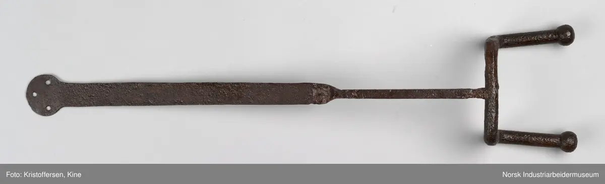 Denne gjenstanden er funnet i ett eller annet av jernbanens bygg. Gjenstanden framkommer som hel og fin og i god stand. Den har ingen slitasjemerker. Det er umulig å si om det har vært spiker eller skruer gjennom hullene og om den dermed har vært hengt opp eller festet på noen måte. Lengden på hele gjenstanden er 81 cm. Det er en skjøt på skaftet, som tyder på at to deler er sveiset sammen. Gjenstanden er forsiktig konservert foran utstillingen på Rjukan stasjon, det vil si at den er pusset med fint sandpapir og har fått et tynt lag voks. 
Ingen vet hvor den kommer fra, hvor den hører til eller hva den har vært brukt til.