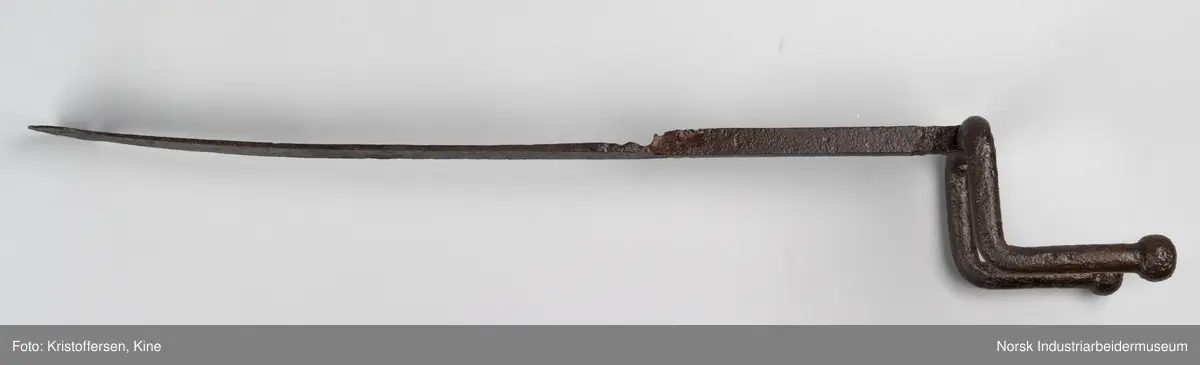 Denne gjenstanden er funnet i ett eller annet av jernbanens bygg. Gjenstanden framkommer som hel og fin og i god stand. Den har ingen slitasjemerker. Det er umulig å si om det har vært spiker eller skruer gjennom hullene og om den dermed har vært hengt opp eller festet på noen måte. Lengden på hele gjenstanden er 81 cm. Det er en skjøt på skaftet, som tyder på at to deler er sveiset sammen. Gjenstanden er forsiktig konservert foran utstillingen på Rjukan stasjon, det vil si at den er pusset med fint sandpapir og har fått et tynt lag voks. 
Ingen vet hvor den kommer fra, hvor den hører til eller hva den har vært brukt til.
