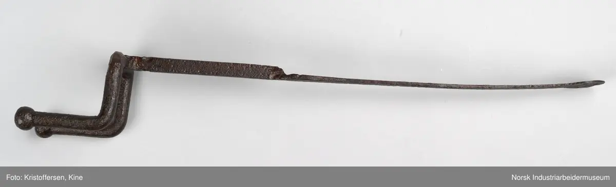 Denne gjenstanden er funnet i ett eller annet av jernbanens bygg. Gjenstanden framkommer som hel og fin og i god stand. Den har ingen slitasjemerker. Det er umulig å si om det har vært spiker eller skruer gjennom hullene og om den dermed har vært hengt opp eller festet på noen måte. Lengden på hele gjenstanden er 81 cm. Det er en skjøt på skaftet, som tyder på at to deler er sveiset sammen. Gjenstanden er forsiktig konservert foran utstillingen på Rjukan stasjon, det vil si at den er pusset med fint sandpapir og har fått et tynt lag voks. 
Ingen vet hvor den kommer fra, hvor den hører til eller hva den har vært brukt til.