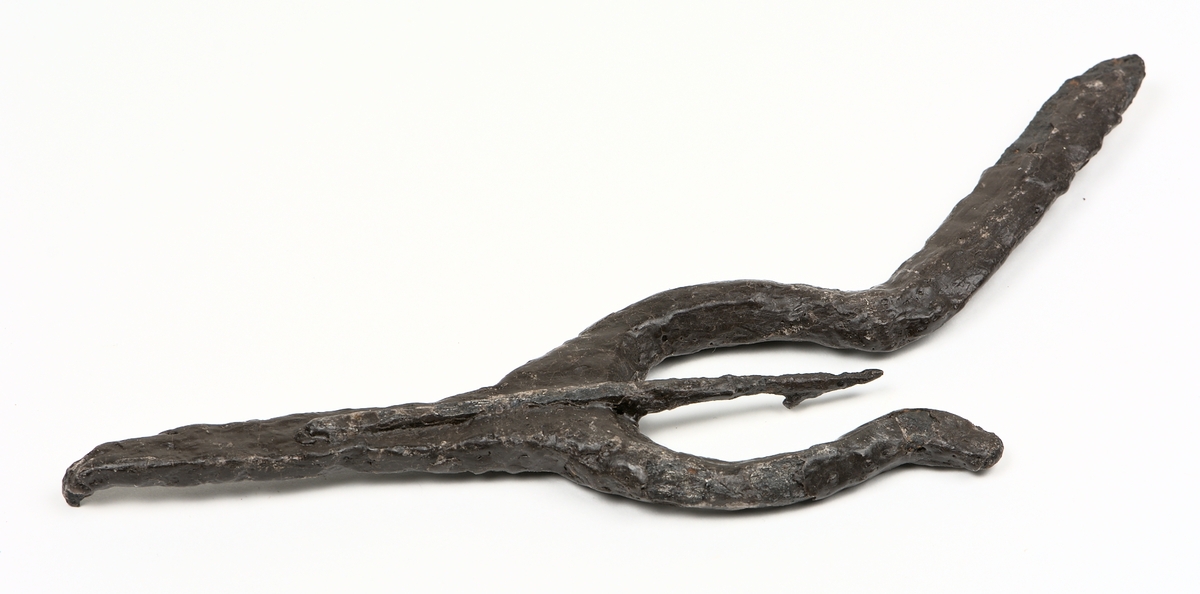 Ljuster av järn med spets inom starka, lyraformade sidostycken, som mitt för spetsen böjer av snett utåt sidorna.