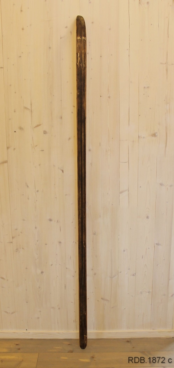 Avsmalende jevnbred ski med liten bue. Bøy uten tupp. Tilspisset brettende.
Dekorert med ei brun stripe på trehvit bunn.

Stempel fra 1960-sesongen på skiet.