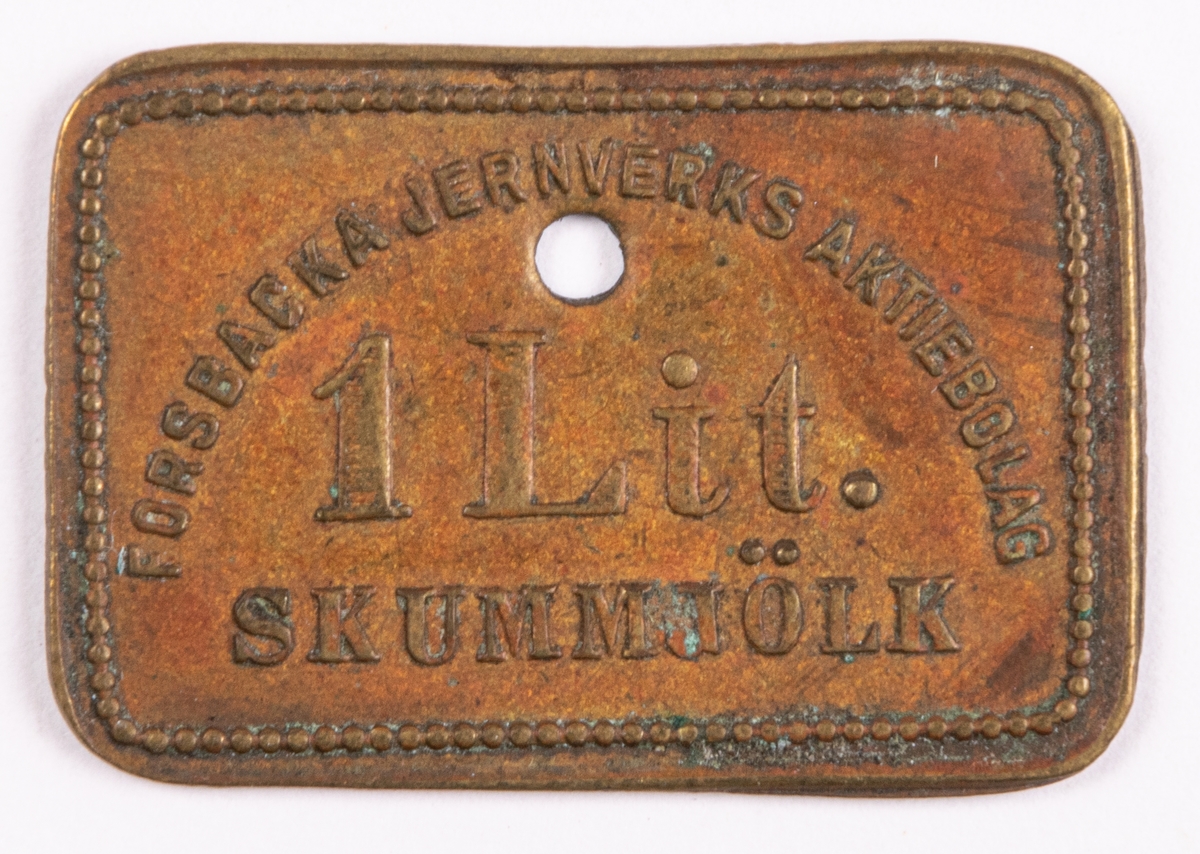 Mjölkpoletter av mässing förvarade i bleckplåtslåda.
Text på de rektangulara brickorna:
FORSBACKA JERNVERKS AKTIEBOLAG 1Lit. SKUMMJÖLK. Poletternas mått: 21 x 32 mm.
Lådan 230x215 mm.