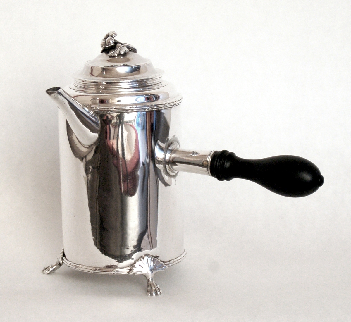 a) Kaffekanna, silver. Cylindrisk form. Koniskt rörformad pip, lätt svängd. Horisontellt skaft av svart trä. Längs vattenkanten och vid övergången till lockpartiet finns en dekorativ bård: Lejontassar till fötter.
Stämplad: bl.a. "Zethelius" , "P" och  kattfot.
Monogram: P. E.

b) Lock, silver. Lätt trappstegsformat med en blomma som lockknopp.
Stämpel: "SR", kattfot och "R2".
Mått: h 4cm, diam 7,5cm.

Härkomst: 
a) Stockholm, Peht Zethelius 1773.
b) Stockholm, Simson Ryberg 1799.
Stil: Gustavianskt.