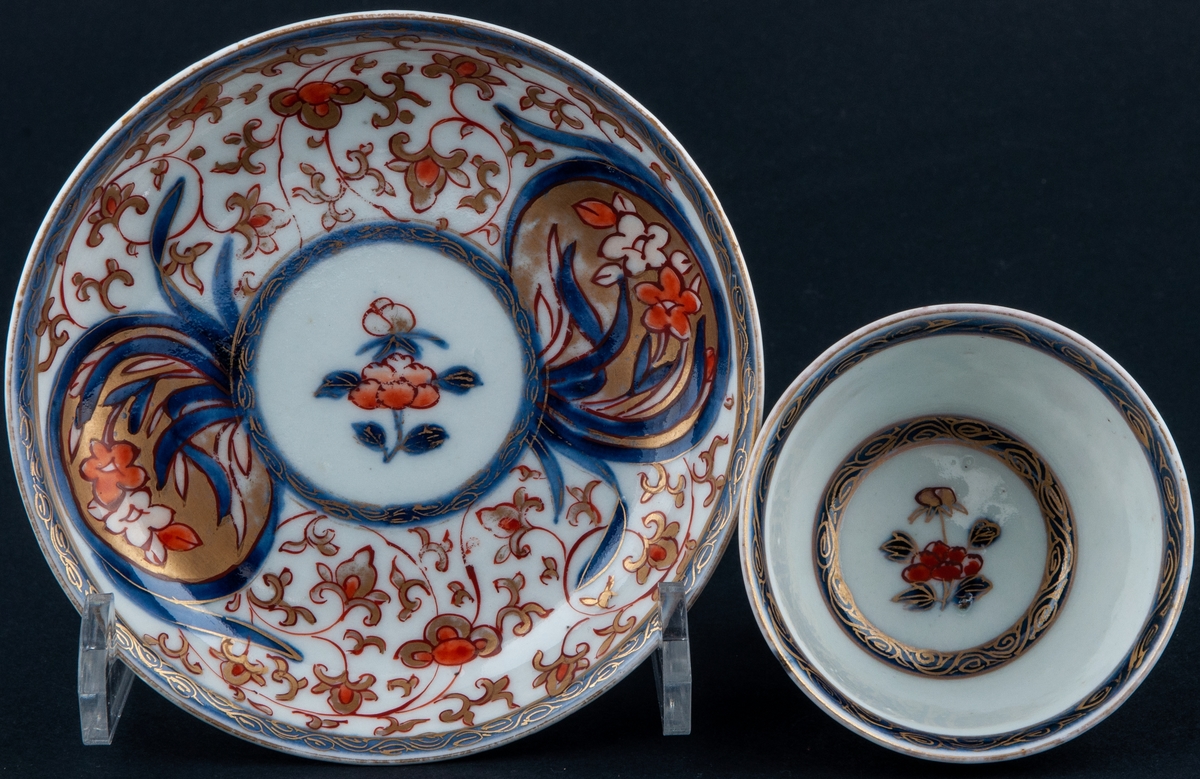 Kopp och fat, kopp utan öra. Vit glasyr med överglasyrmålning i blått, orange och guld. Utan stämpel, kompaniporslin.