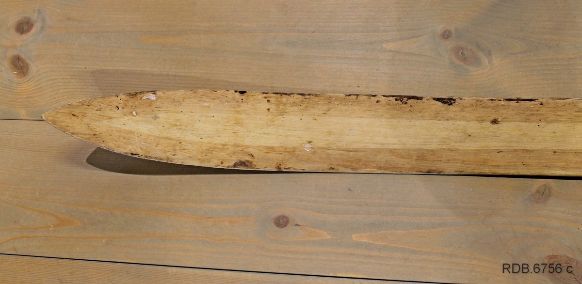 Et heimeprodusert treski. Sålen på skiet er borte, slik at en kan se hvordan det er laget invendig. Overplata har mørke striper langs kanten og en lys stripe etter midten. Skiet er jevnbredt med tverr bakkant, bred brett med lav bøy. Skiet er bredest på midten og smalere bak- og framover. Spikermerker etter bindinger og fotplate som er fjernet. Innvendig er det 4 "luftrom" som gjør skiet lettere.