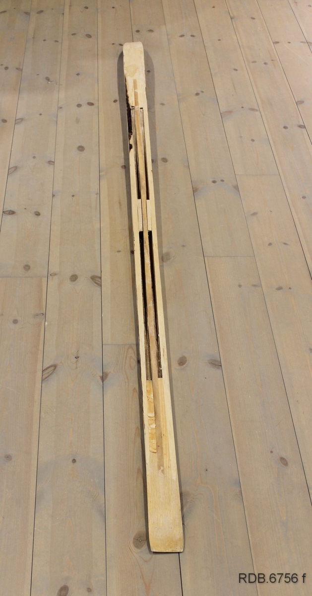 Et heimeprodusert treski. Sålen på skiet er borte, slik at en kan se hvordan det er laget invendig. Overplata har mørke striper langs kanten og en lys stripe etter midten. Skiet er jevnbredt med tverr bakkant, bred brett med lav bøy. Skiet er bredest på midten og smalere bak- og framover. Spikermerker etter bindinger og fotplate som er fjernet. Innvendig er det 4 "luftrom" som gjør skiet lettere.