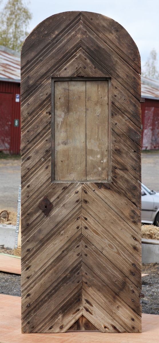 Døra er laget av 1 1/4 toms planker med to enkle drev som holder plankene sammen. Døra er belagt med profilert panel. Panelet er lagt på skrå i mønemønster og festet med spiker som har digre hoder. Døra har et vindu på 45 cm x 79 cm som innvendig er lukket med en liten hengslet dør. Døra er nærmest halvsirkelformet i toppen og passer da inn i buen i murverket. Låsen sitter på og har rombeformet nøkkelhullbeslag og to solide gangjern med to enkle knuter. Låsen sitter på innsida og er helt innebygd med jernplater og to slåtter. På innsida er rester etter påmalt marmorering.