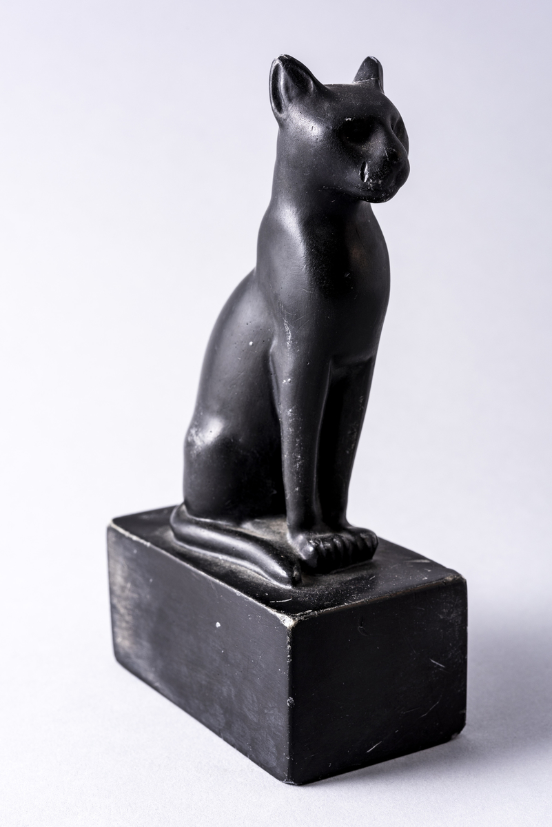 Figur i sortmalt keramikk av katt på firkantet base. Har tilhørt Sara Fabricius.