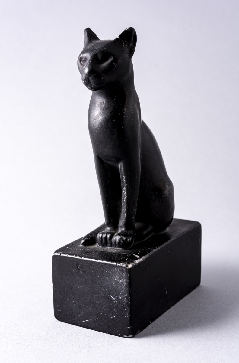 Figur i sortmalt keramikk av katt på firkantet base. Har tilhørt Sara Fabricius.