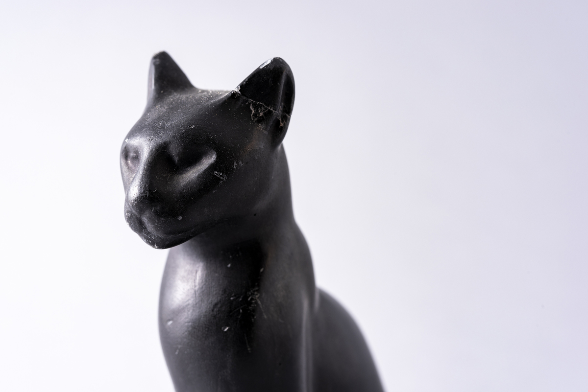 Figur i sortmalt keramikk av katt på firkantet base. Har tilhørt Sara Fabricius.