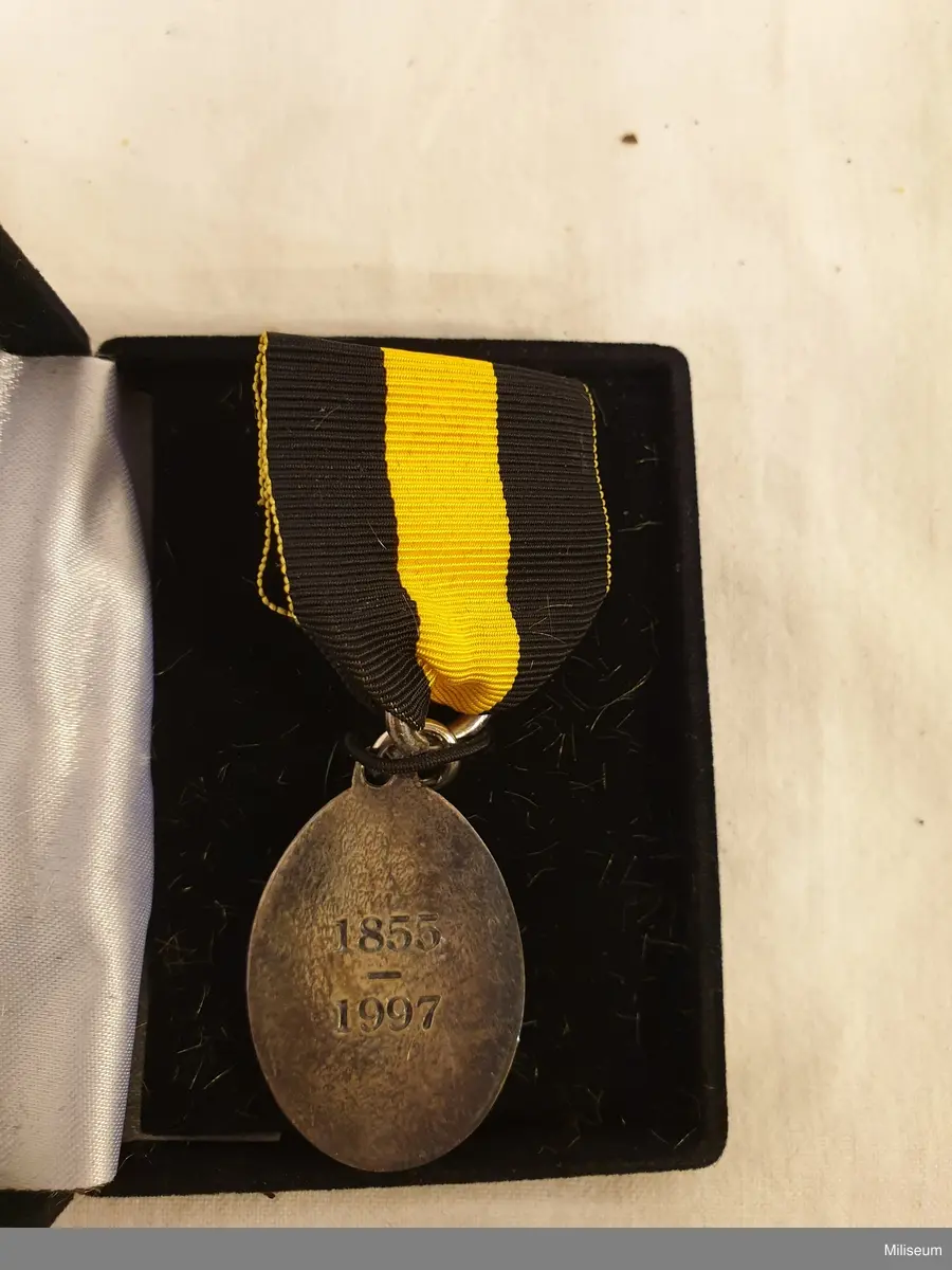 Hemvärnets förtjänstemedalj i valören silver, tillverkad av försilvrad mässing, med tillhörande bandspänne, extra ripsband och etui av svart plast.