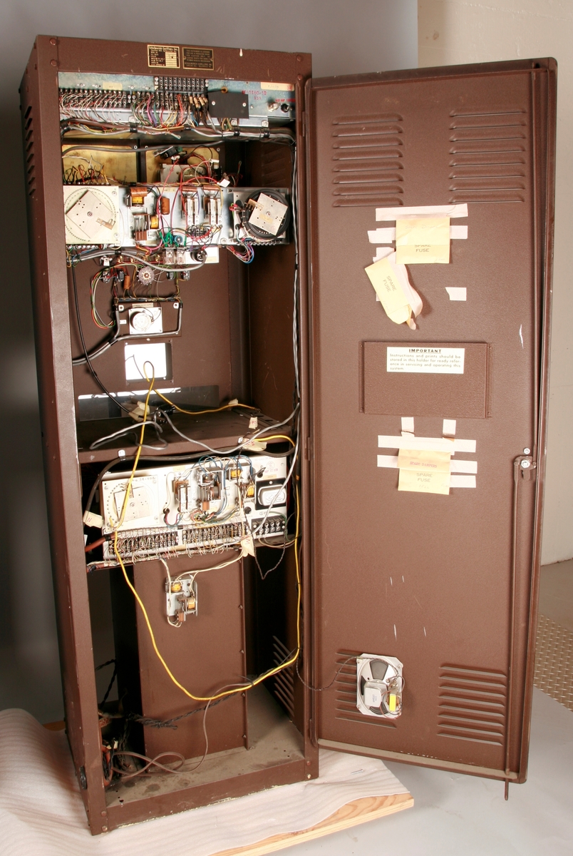 To brunmalte skap i metall (samme størrelse). Flere ventilasjonsrister.

Det ene skapet (A) inneholder avspiller, forsterker, klokkemekanikk, liten høytaler og øvrig elektronikk (noen deler ser ut å mangle). 
Øvre halvdel: bak pleksiglass som kan lukkes er styresentralen med instillinger for ulike klokkeprogrammer:
Til høyre er switch-knapper for å aktivere de tre funksjonene 
a) avspilling av musikkrull 
b) bruk av manuelt spillebord og 
c) timeslag.

Over til venstre er en timer for å skjemalegge de ulike aktivitetene:
1) Hverdag avspilling musikkrull
2) Søndag avspilling musikkrull
3) Hverdag avspilling timeslag
4) Søndag avspilling timeslag
5) Hverdag avspilling manuelt spillebord
6) Søndag avspilling manuelt spillebord

I tillegg er et eget panel for å velge ulike fomer av klokkeringinger ('BELL PEAL').

Nedre halvdel: Musikkrullmekanikk med en mekanisk avleser for musikkrullene ('tracker bar'). 30 spor; én for én tone hver. Papirullen løper over en rekke fjærbelastede(?) L-formet tangenter, en for hvert spor. Når et hull passerer en tangent løftes tangenten oppover og gir i sin tur et signal videre om å aktivere akkurat denne tonen.

Det andre skapet (B) idag tomt, usikker funksjon. Har strømforsyning. Sannsynlig forsterker for bruk av høytalere (C-F) i klokketårnet. Se elektronikk (H). Muligens også oppbevaring av musikkruller med mer.