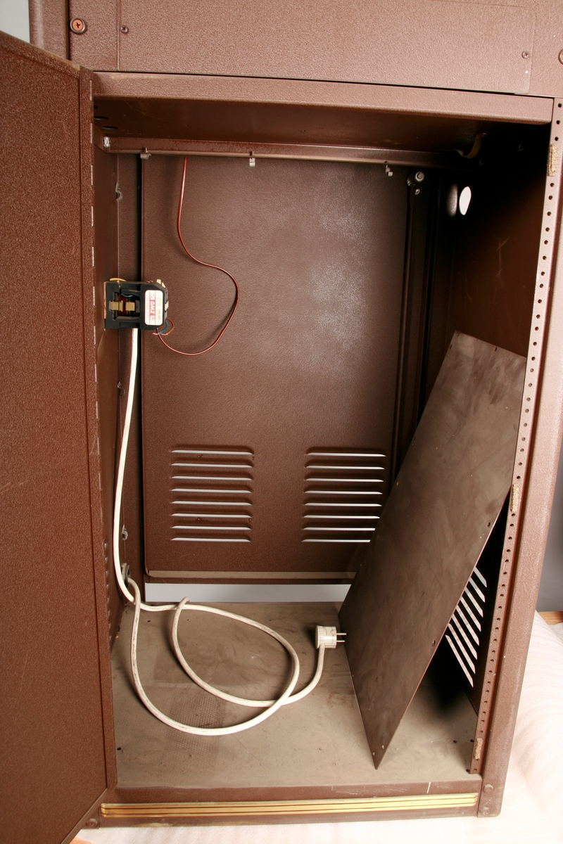 To brunmalte skap i metall (samme størrelse). Flere ventilasjonsrister.

Det ene skapet (A) inneholder avspiller, forsterker, klokkemekanikk, liten høytaler og øvrig elektronikk (noen deler ser ut å mangle). 
Øvre halvdel: bak pleksiglass som kan lukkes er styresentralen med instillinger for ulike klokkeprogrammer:
Til høyre er switch-knapper for å aktivere de tre funksjonene 
a) avspilling av musikkrull 
b) bruk av manuelt spillebord og 
c) timeslag.

Over til venstre er en timer for å skjemalegge de ulike aktivitetene:
1) Hverdag avspilling musikkrull
2) Søndag avspilling musikkrull
3) Hverdag avspilling timeslag
4) Søndag avspilling timeslag
5) Hverdag avspilling manuelt spillebord
6) Søndag avspilling manuelt spillebord

I tillegg er et eget panel for å velge ulike fomer av klokkeringinger ('BELL PEAL').

Nedre halvdel: Musikkrullmekanikk med en mekanisk avleser for musikkrullene ('tracker bar'). 30 spor; én for én tone hver. Papirullen løper over en rekke fjærbelastede(?) L-formet tangenter, en for hvert spor. Når et hull passerer en tangent løftes tangenten oppover og gir i sin tur et signal videre om å aktivere akkurat denne tonen.

Det andre skapet (B) idag tomt, usikker funksjon. Har strømforsyning. Sannsynlig forsterker for bruk av høytalere (C-F) i klokketårnet. Se elektronikk (H). Muligens også oppbevaring av musikkruller med mer.