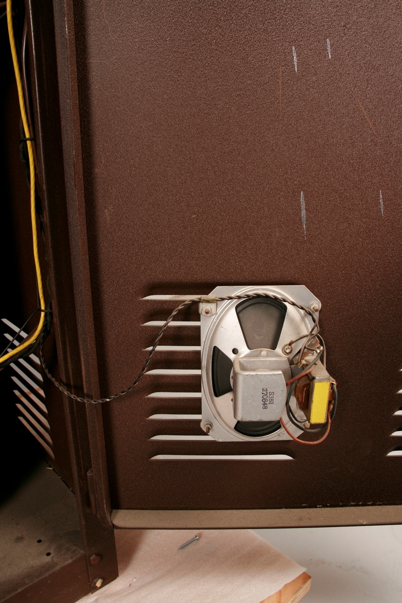 To brunmalte skap i metall (samme størrelse). Flere ventilasjonsrister.

Det ene skapet (A) inneholder avspiller, forsterker, klokkemekanikk, liten høytaler og øvrig elektronikk (noen deler ser ut å mangle). 
Øvre halvdel: bak pleksiglass som kan lukkes er styresentralen med instillinger for ulike klokkeprogrammer:
Til høyre er switch-knapper for å aktivere de tre funksjonene 
a) avspilling av musikkrull 
b) bruk av manuelt spillebord og 
c) timeslag.

Over til venstre er en timer for å skjemalegge de ulike aktivitetene:
1) Hverdag avspilling musikkrull
2) Søndag avspilling musikkrull
3) Hverdag avspilling timeslag
4) Søndag avspilling timeslag
5) Hverdag avspilling manuelt spillebord
6) Søndag avspilling manuelt spillebord

I tillegg er et eget panel for å velge ulike fomer av klokkeringinger ('BELL PEAL').

Nedre halvdel: Musikkrullmekanikk med en mekanisk avleser for musikkrullene ('tracker bar'). 30 spor; én for én tone hver. Papirullen løper over en rekke fjærbelastede(?) L-formet tangenter, en for hvert spor. Når et hull passerer en tangent løftes tangenten oppover og gir i sin tur et signal videre om å aktivere akkurat denne tonen.

Det andre skapet (B) idag tomt, usikker funksjon. Har strømforsyning. Sannsynlig forsterker for bruk av høytalere (C-F) i klokketårnet. Se elektronikk (H). Muligens også oppbevaring av musikkruller med mer.