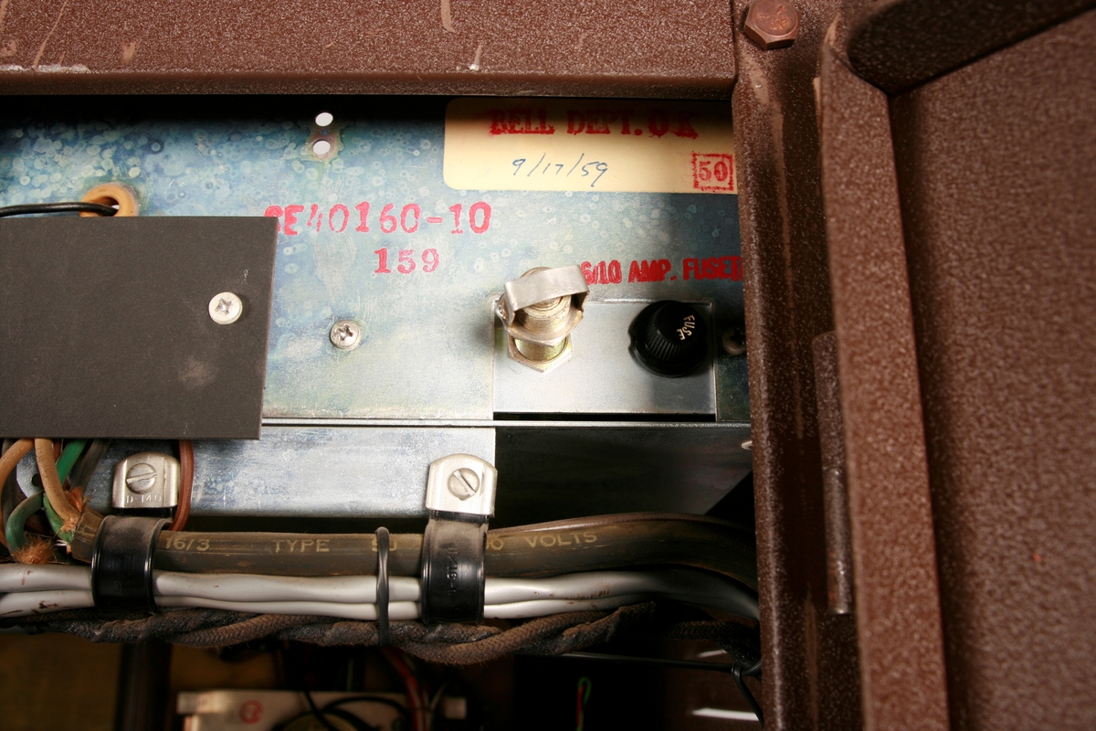 To brunmalte skap i metall (samme størrelse). Flere ventilasjonsrister.

Det ene skapet (A) inneholder avspiller, forsterker, klokkemekanikk, liten høytaler og øvrig elektronikk (noen deler ser ut å mangle). 
Øvre halvdel: bak pleksiglass som kan lukkes er styresentralen med instillinger for ulike klokkeprogrammer:
Til høyre er switch-knapper for å aktivere de tre funksjonene 
a) avspilling av musikkrull 
b) bruk av manuelt spillebord og 
c) timeslag.

Over til venstre er en timer for å skjemalegge de ulike aktivitetene:
1) Hverdag avspilling musikkrull
2) Søndag avspilling musikkrull
3) Hverdag avspilling timeslag
4) Søndag avspilling timeslag
5) Hverdag avspilling manuelt spillebord
6) Søndag avspilling manuelt spillebord

I tillegg er et eget panel for å velge ulike fomer av klokkeringinger ('BELL PEAL').

Nedre halvdel: Musikkrullmekanikk med en mekanisk avleser for musikkrullene ('tracker bar'). 30 spor; én for én tone hver. Papirullen løper over en rekke fjærbelastede(?) L-formet tangenter, en for hvert spor. Når et hull passerer en tangent løftes tangenten oppover og gir i sin tur et signal videre om å aktivere akkurat denne tonen.

Det andre skapet (B) idag tomt, usikker funksjon. Har strømforsyning. Sannsynlig forsterker for bruk av høytalere (C-F) i klokketårnet. Se elektronikk (H). Muligens også oppbevaring av musikkruller med mer.