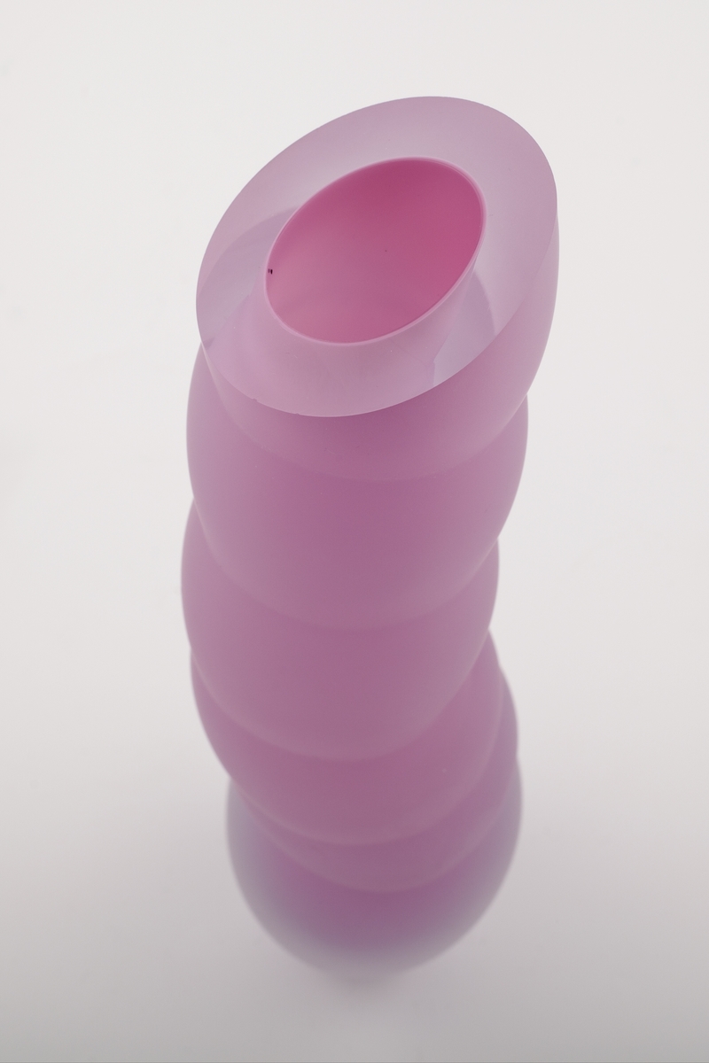 Vase i underfangsglass. Et sjikt i opakt lillafarget glass innerst, deretter et tykt sjikt i klart glass. Flerleddet kuleformet korpus, hvis ytterside er mattet ved hjelp av sandblåsing. Vasens sirkulære munning er planslipt.