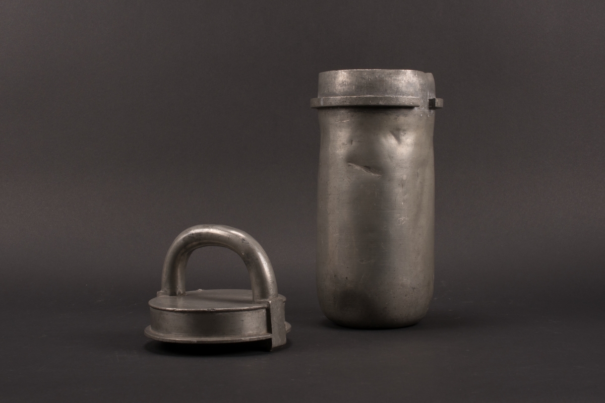 Cylindrisk glassform av tenn. Lock med halvcirkelformat handtag. Formens botten är något rundad.