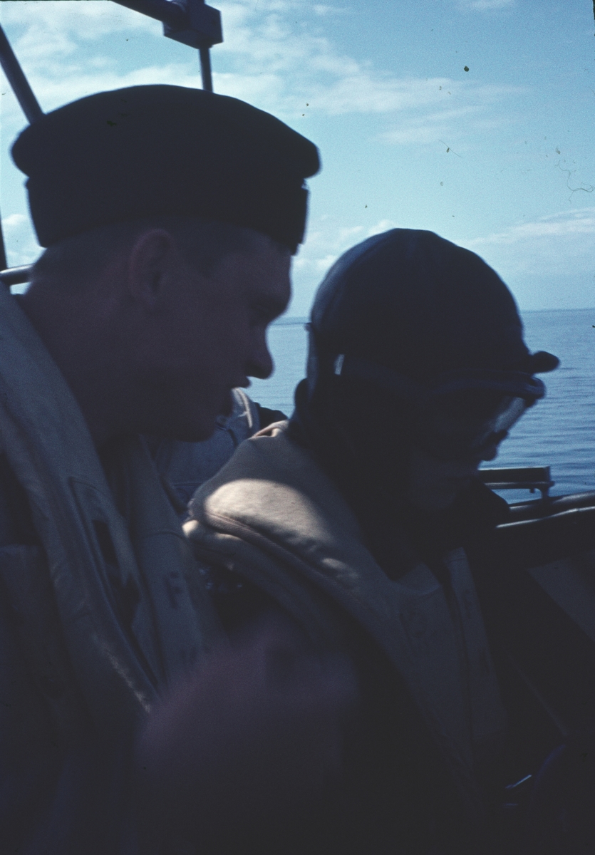 Bilden visar en besättningsmän med besökare i skyddskläder ombord på en motortorpedbåt.