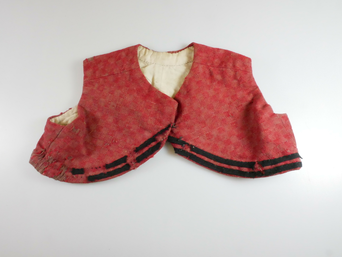 Rødt livstykke i ull med hvitt for. To svarte parallelle bånd nederst rundt livstykket. Tre metallhekter foran. 