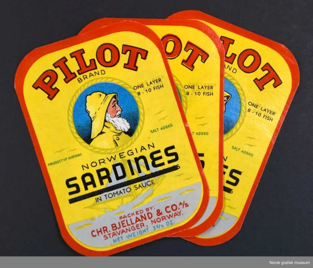 Etiketter med gul bakgrunn og rød ramme. Sentralt på etiketten er en illustrasjon av en hvitskjegget mann med gul sydvest i profil. 

"Norwegian sardines in tomato sauce"