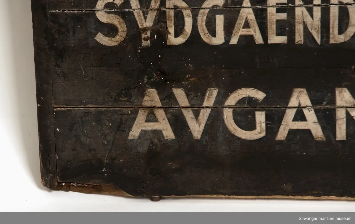 Svartmalt treskilt med påmalt DSD, postflagget og rutefartinformasjon.
