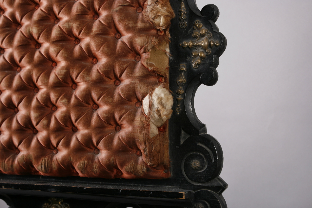 Notestativ i sortmalt tre. Notestol og fot kan settes sammen, foten deler seg i tre nederst. Rike profileringer på fot og stol, messingbeslag som er hamret i naturalistiske og stiliserte ornamenter. Stolen er på forsiden trukket med rustrødt, stoppet sikestoff. Denne kan reguleres på baksiden. Her kan men se merker etter to lister som sannsynligvis er det gamle festet mellom stol og fot.