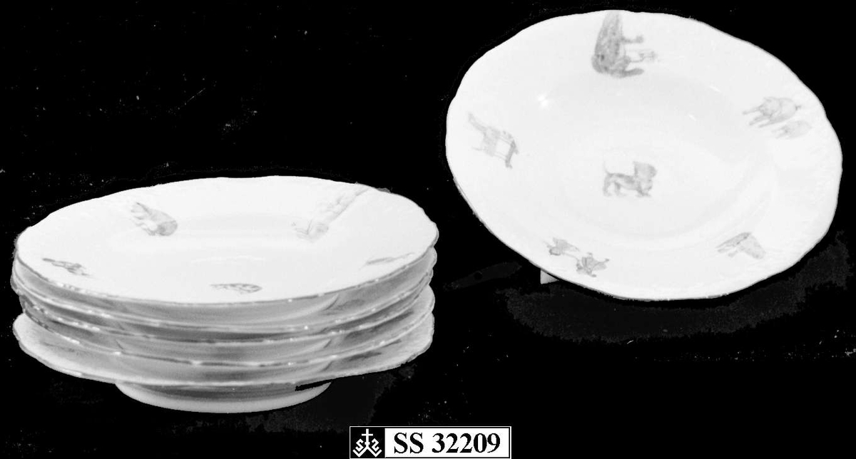 Seks leketallerkener av glassert keramikk. Randen er bølgete og har en dekorativ grønn stripe. Flerfarget trykk med motiv av dyr og leker, hver tallerken har forskjellige kombinasjoner av trykkene.