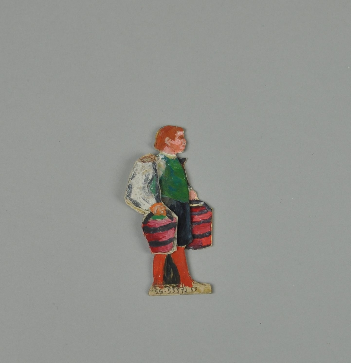 Figur av papp. Figuren forestiller gutt i sideprofil, med hendene i lommen. En annen del kan skyves over figuren, slik at gutten holder to bøtter. Figuren er malt på begge sider.