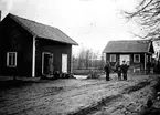 TVÅ MÄN OCH ETT BARN FRAMFÖR EN KVARNBYGGNAD, TILL VÄNSTER ETT UTHUS PÅ KVARNBOLET I FREDSBERG