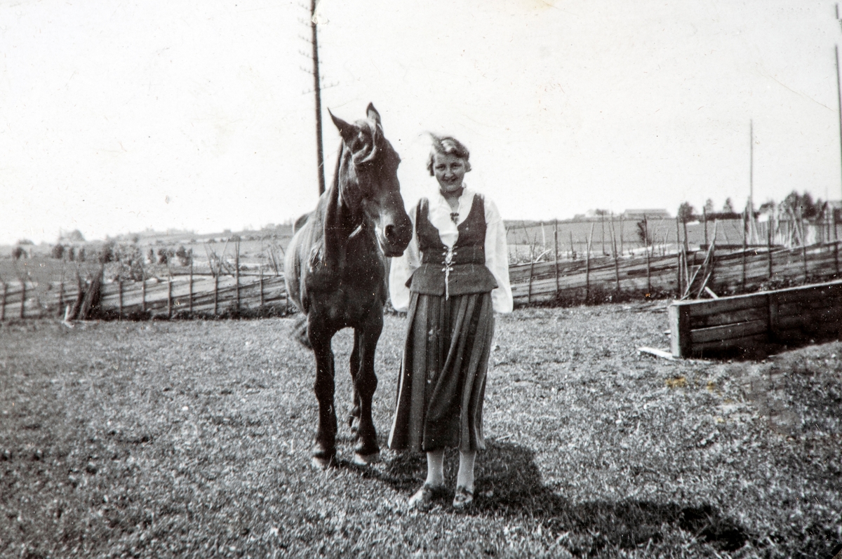 Ukjent dame i bunad, holder en hest.