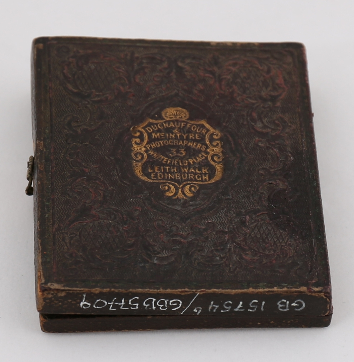 Daguerreotypi av mann som sitter ved et bord. Håndkolorerte hudtoner.