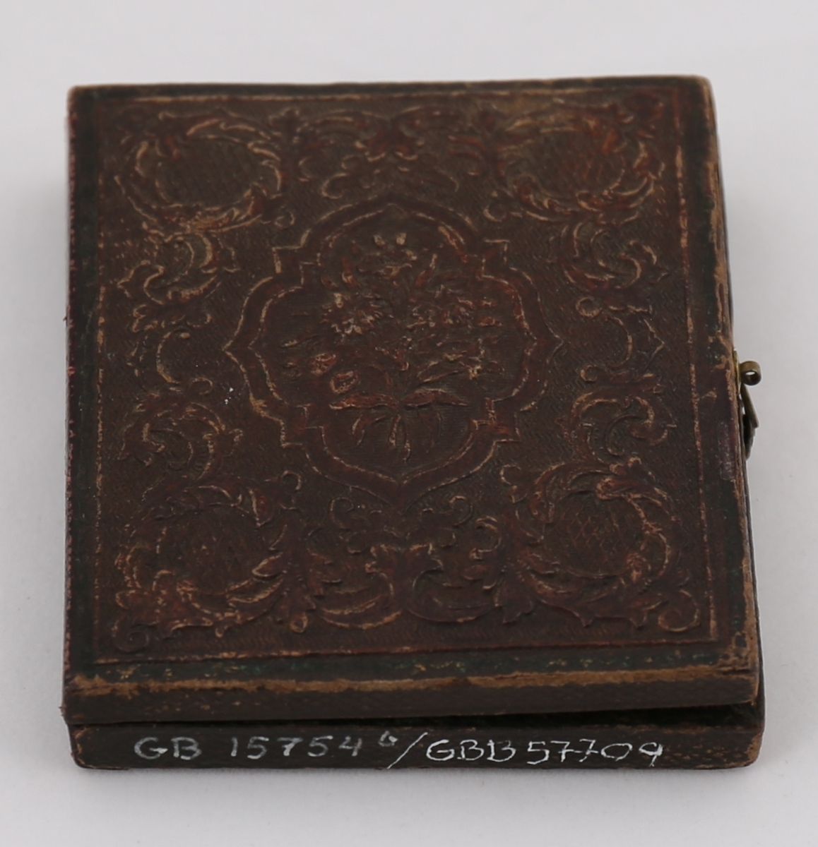 Daguerreotypi av mann som sitter ved et bord. Håndkolorerte hudtoner.