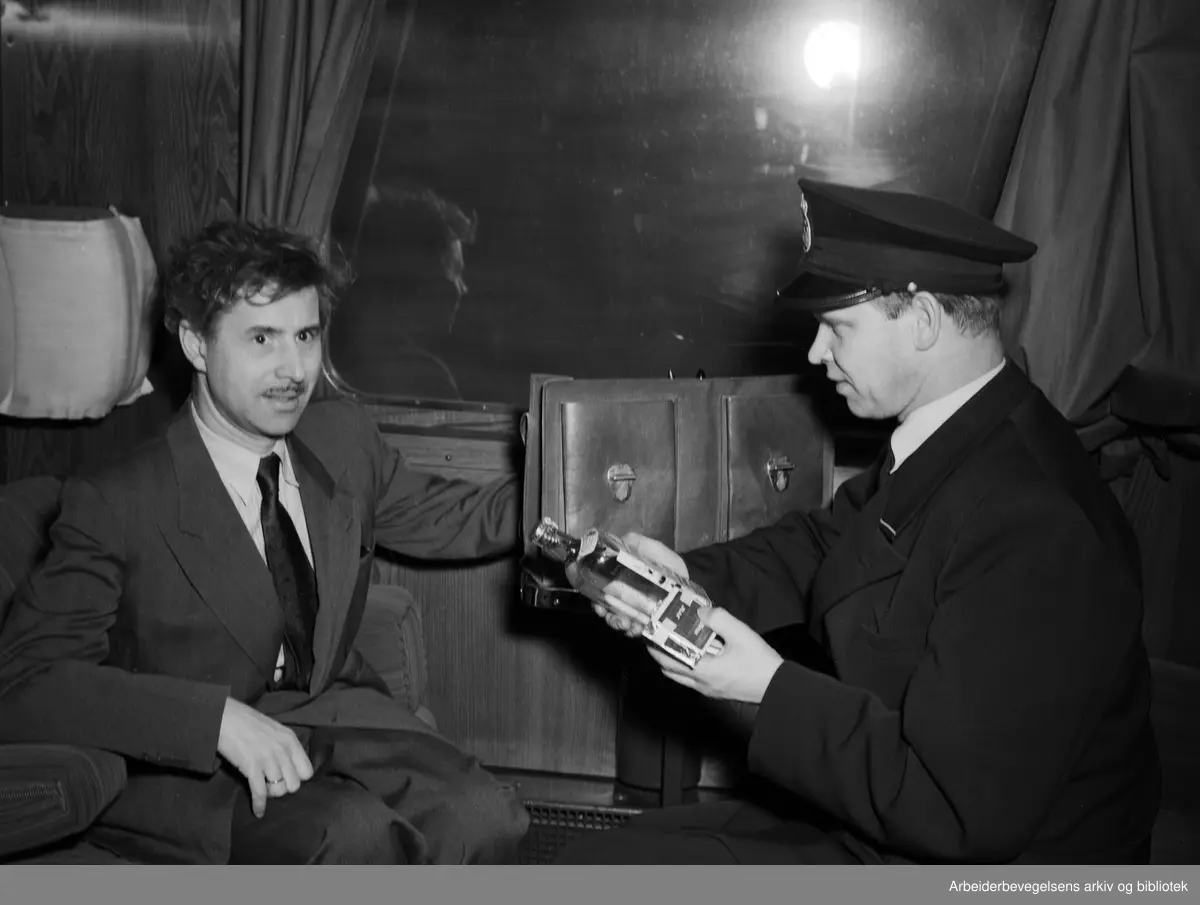 Den svenske tolleren Fritjof Falckstrand (t.h.) sjekker bagasjen til togpassasjer Kaare Strøm, som er på vei fra Oslo til Gøteborg. (Professor og limnolog Kaare Strøm 1902-1967). November 1951.
