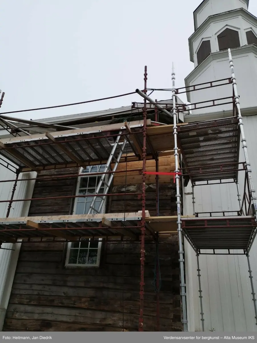 Originale bygningsdeler fra Alta kirke i Bossekop. Tømmerbit fra kirkas laftede innerbygg, dimling brukt for å avstive laftestokker, samt tretten håndsmidde spikere.