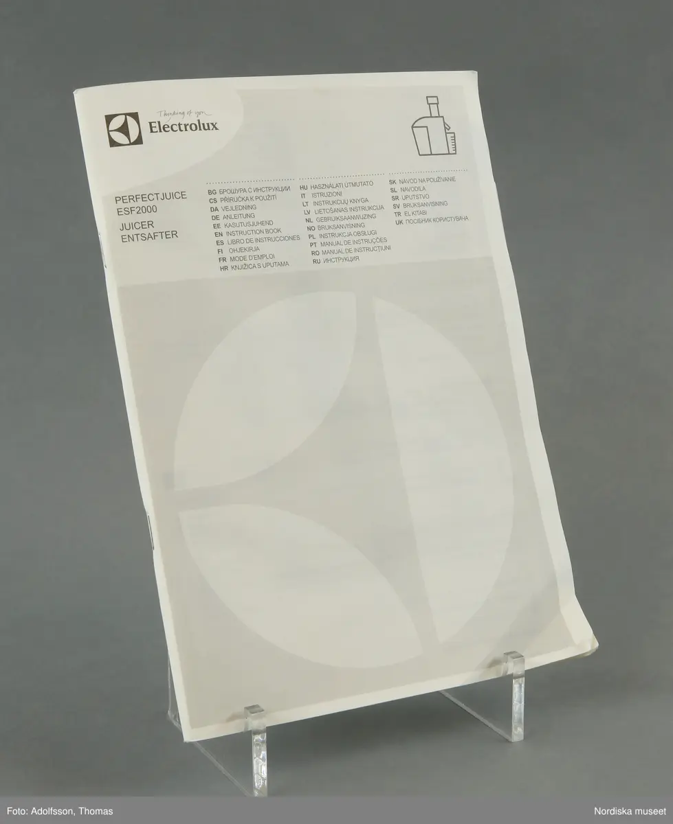 En elektrisk råsaftcentrifug av märket Elektrolux PERFECTJUICE ESF 2000. Består av  6 delar. a) Själva råsaftcentrifugen är cylinderformad och av metall och plast. De övriga delarna är av rökgrå hårdplast och består av b+) ett lock med c) press samt en d) behålllare som fruktköttet samlas i och e) en liten lockförsedd juicekanna med f) skumseparator i form av en plasskena som saften rinner ut i när den är klar. Dessutom en g) bruksanvisningsbroschyr och ett h) garantipapper.
Locket (b+) har en skada där en bit är avslagen.

Lena Kättström Höök 2014-01-10