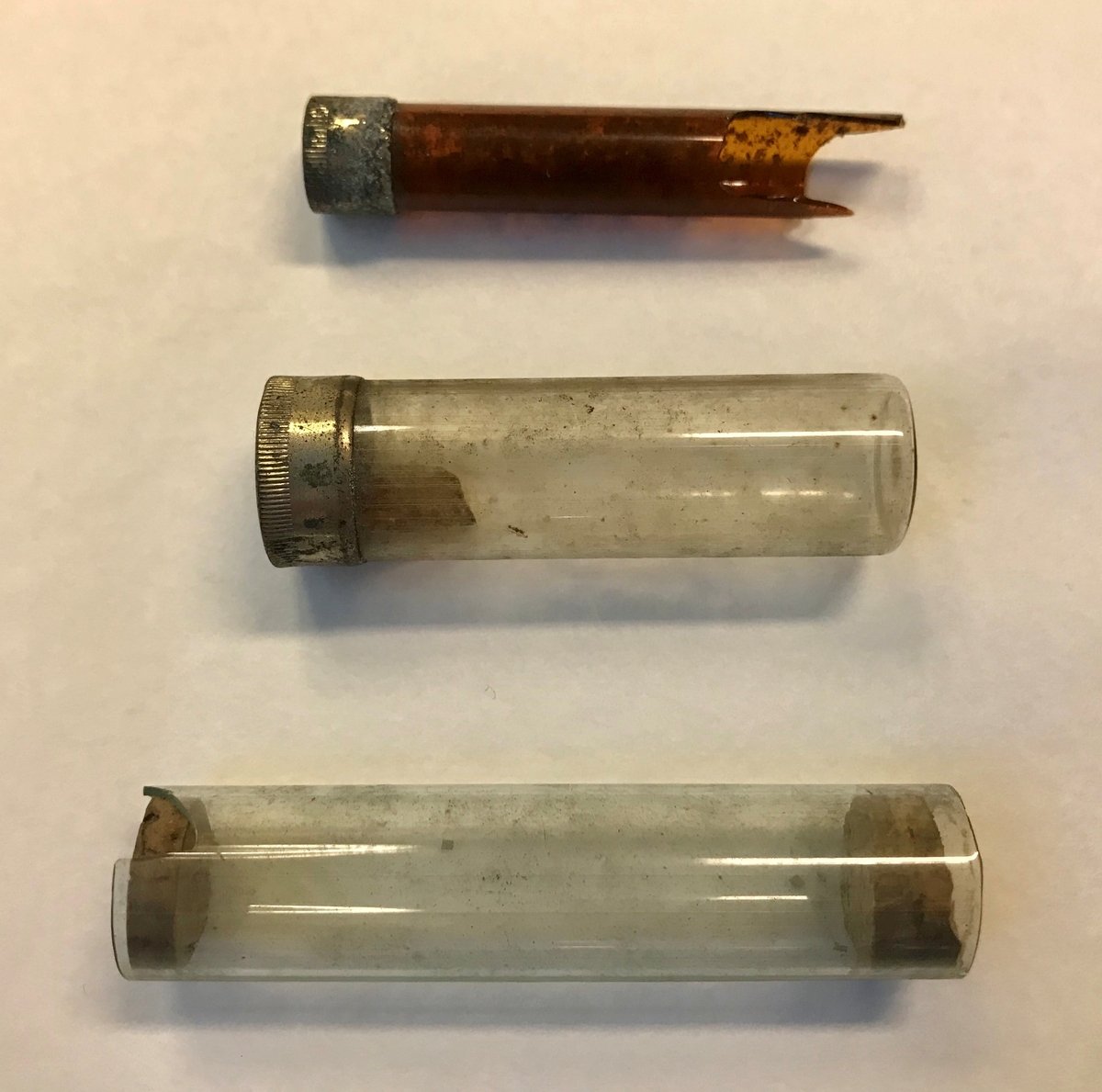 Geologiske prøver og bombedeler. Seks glassrør, en dreid trepropp og en liten beholder i tre. 

Trebeholderen inneholder tre små spisse pinner av ukjent materiale, muligens tennsatser. Et av de brune glassrørene inneholder små metallsylindre. Dette er trolig tennhetter .Et av rørene inneholder en liten glassbit, resten er tomme. Et av rørene er knust.